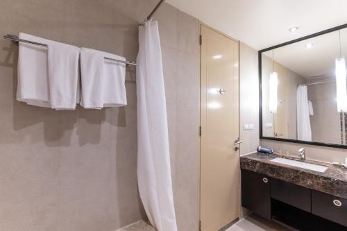 a bathroom with a shower and a sink and a mirror at Admiral Premier Bangkok in Bangkok