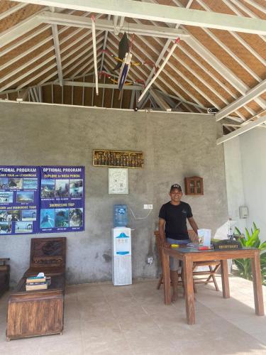 a man sitting at a table with a laptop at Paluh Beach Huts in Nusa Lembongan