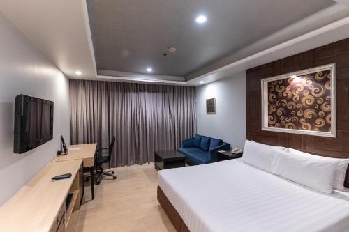 a hotel room with a bed and a desk and a tv at Admiral Premier Bangkok in Bangkok