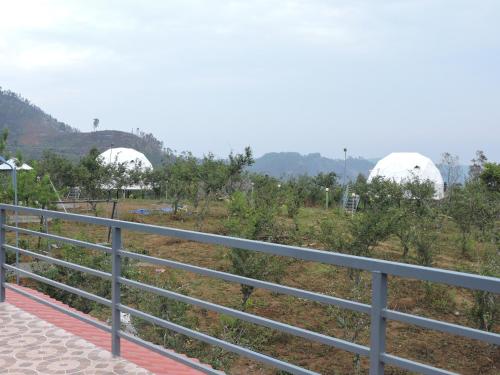 a fence with domes in a field with trees at L.T NATURE GLAMPS in Kodaikānāl