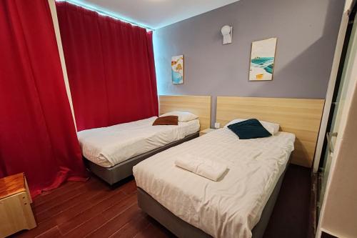 two beds in a small room with red curtains at Hotel 18 Ipoh Aeon Mall in Ipoh