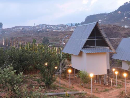 a building with lights in front of a vineyard at L.T NATURE GLAMPS in Kodaikānāl