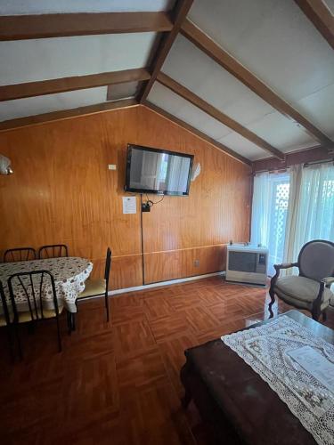 a living room with a table and a tv on the wall at Cabañas Español Coyhaique in Coihaique