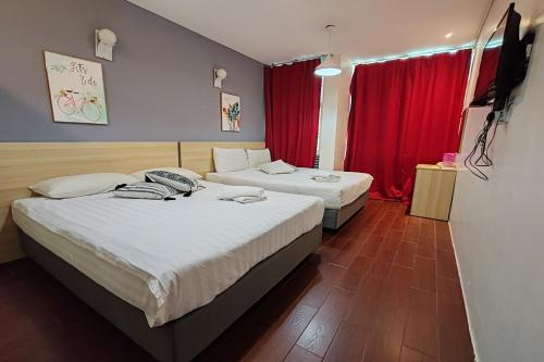 two beds in a hotel room with red curtains at Hotel 18 in Ipoh