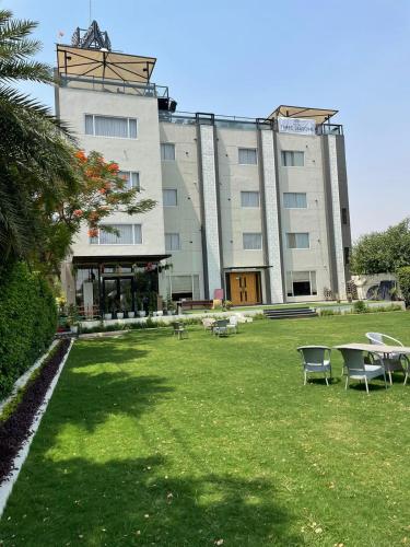 a large building with tables and chairs in the grass at Hotel Three Seasons in Vrindāvan