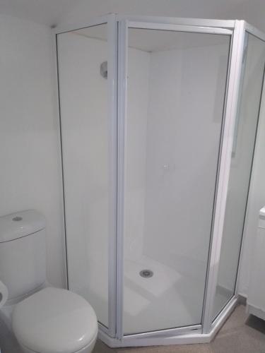 a shower with a glass door next to a toilet at South Brighton Holiday Park in Christchurch