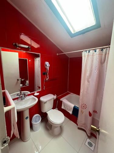 a red bathroom with a toilet and a sink at Cabañas Español Coyhaique in Coihaique