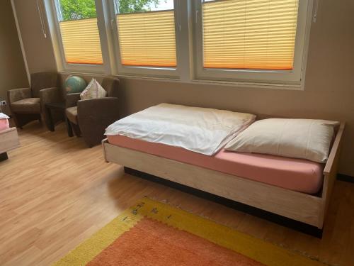 a bedroom with a bed and a chair and windows at Hotel Am Sportpark in Duisburg