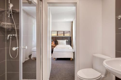 a bathroom with a toilet and a bed in a room at Waldhotel in Mainz