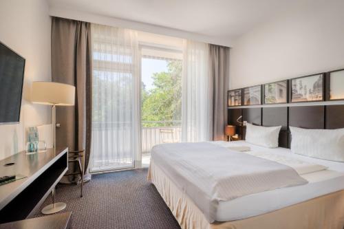 a bedroom with a large bed and a large window at Waldhotel in Mainz