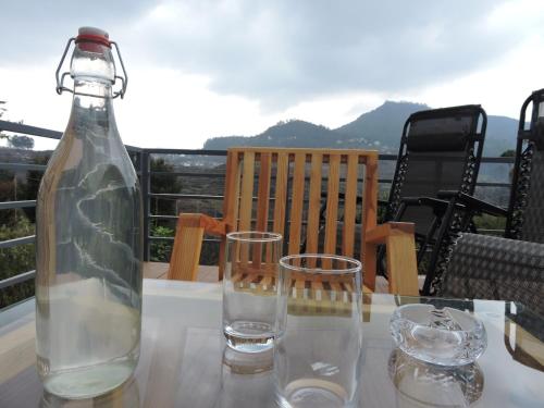 a bottle and two glasses sitting on a table at L.T NATURE GLAMPS in Kodaikānāl
