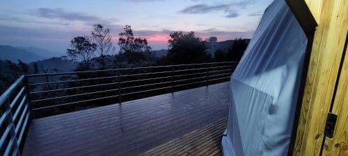 a balcony of a house with a view of the sunset at L.T NATURE GLAMPS in Kodaikānāl