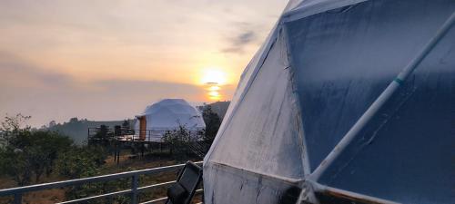 a view of a tent with the sunset in the background at L.T NATURE GLAMPS in Kodaikānāl