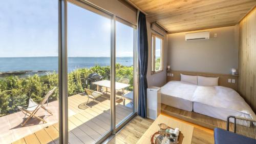 a bedroom with a bed and a balcony with the ocean at La vista Kannonzaki Terrace in Yokosuka