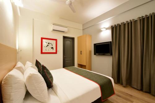 een hotelkamer met een bed en een televisie bij Super Townhouse 106 Airport Road in Yelahanka