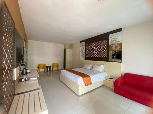 Kalibanteng-lorにあるHotel New Puri Gardenのベッドと赤いソファが備わるホテルルームです。