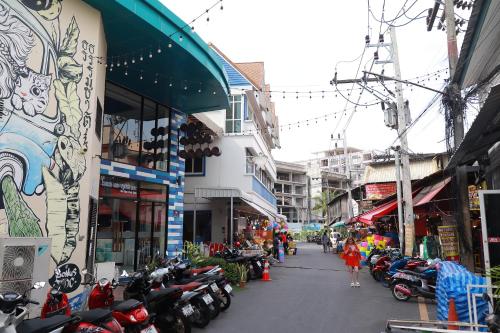 a woman walking down a street next to a bunch of motorcycles at The Blue Pearl Kata Hotel in Kata Beach