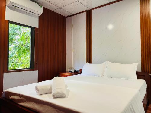 a bedroom with two beds with white sheets and a window at Huy-Mountainside Homestay in Phong Nha