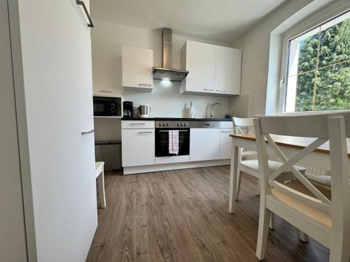 a kitchen with white cabinets and a table and chairs at atrium roselina in Kirchstetten