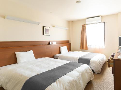 a hotel room with two beds and a window at Vessel Hotel Higashi Hiroshima in Higashihiroshima