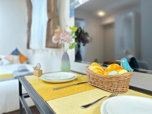 a table with a basket of fruit and plates on it at nestay inn tokyo ueno in Tokyo