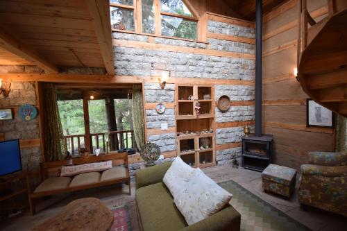 a living room with a couch and a fireplace at Kudrat - A Boutique Homestay- Tirthan Valley in Banjār