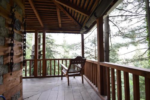 a rocking chair sitting on a porch of a cabin at Kudrat - A Boutique Homestay- Tirthan Valley in Banjār