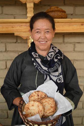 a woman is holding a basket of food at Stone Hedge Hotel in Nubra