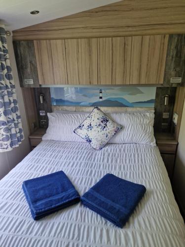 a bed with two blue towels on top of it at HARRIES LODGE QUAY WEST milkwood way in New Quay