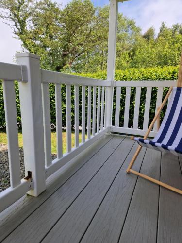 a deck with a rocking chair on a porch at HARRIES LODGE QUAY WEST milkwood way in New Quay