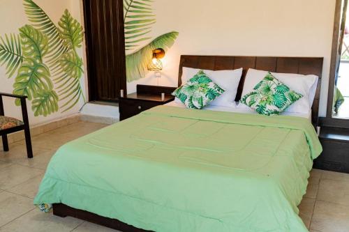 una camera da letto con un grande letto con lenzuola e cuscini verdi di Playa Alta Hostal a Santa Marta