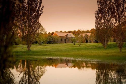 a house in a field next to a body of water at Honeysuckle Barn & Garden in Kyneton