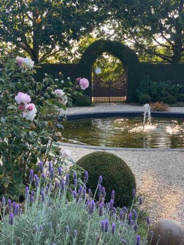 a garden with a pond and a bench and flowers at Honeysuckle Barn & Garden in Kyneton