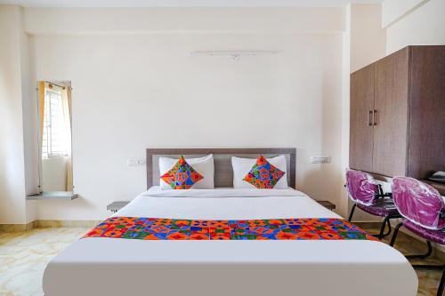 ein Schlafzimmer mit einem großen Bett und zwei lila Stühlen in der Unterkunft FabExpress MS Comforts in Bangalore