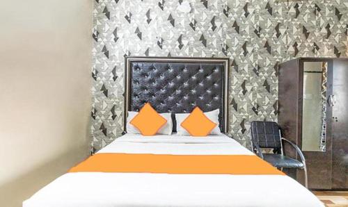 Schlafzimmer mit einem Bett mit einem orangefarbenen Kopfteil in der Unterkunft FabExpress Pavithraa Edition in Bangalore