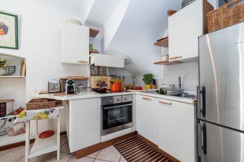  La cuisine est équipée de placards blancs et d'un réfrigérateur. dans l'établissement Les Orangers - Happy Rentals, à Beaulieu-sur-Mer