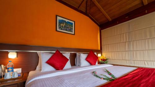 a bedroom with a large bed with red and white pillows at Westwood Riverside in Munnar