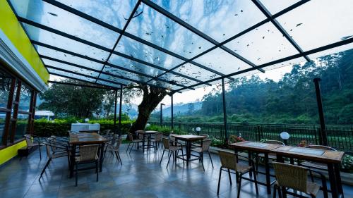 a restaurant with tables and chairs and a large glass ceiling at Westwood Riverside in Munnar