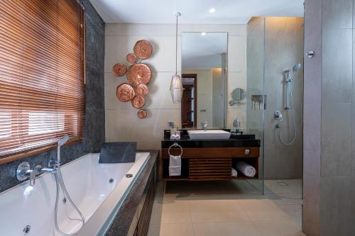 a bathroom with a tub and a sink and a mirror at Tanadewa Villas Nusa Dua Bali by Cross Collection in Nusa Dua