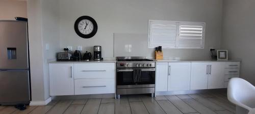 a kitchen with a stove and a clock on the wall at Fairview 17 Yzerfontein South Africa in Yzerfontein