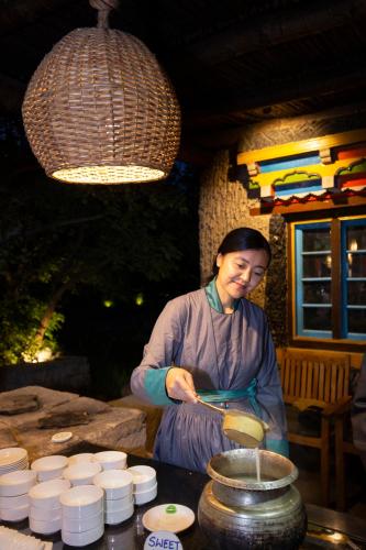 a woman is preparing food in a pot at Organic Village Retreat in Hundar