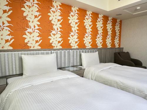 台中市にあるMei Hotelのオレンジと白の壁紙を用いた客室内のベッド2台
