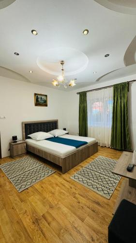 a bedroom with a large bed and green curtains at La Mosu-n Retezat in Nucşoara