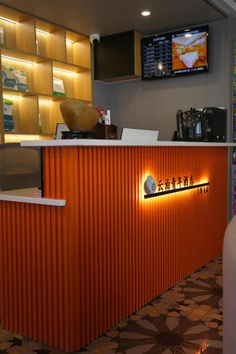 an orange counter in a restaurant with a television at Yunbo Youth Hostel Ürümqi in Ürümqi