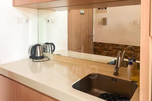 eine Küchentheke mit einem Waschbecken und einem Spiegel in der Unterkunft RedLiving Apartemen Treepark City - Nuansa Property Tower Alpine in Kebonnanas