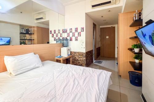 ein Schlafzimmer mit einem weißen Bett und einem Fernseher in der Unterkunft RedLiving Apartemen Treepark City - Nuansa Property Tower Alpine in Kebonnanas