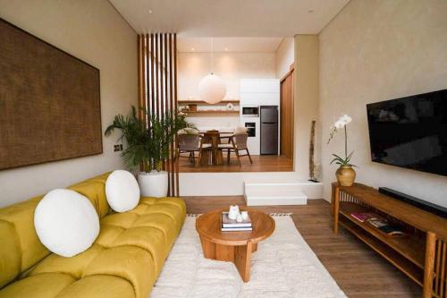 a living room with a yellow couch and a table at Villa Alya Seaside by Pura Homes in Canggu