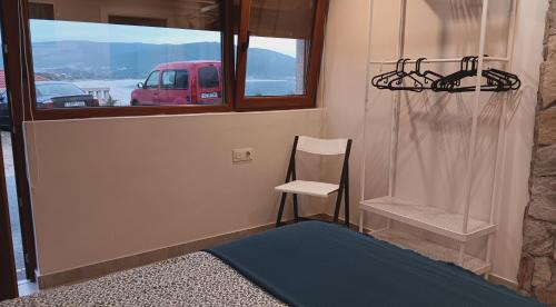 um quarto com uma cama, uma cadeira e uma janela em Pension Doña Lubina em Finisterre