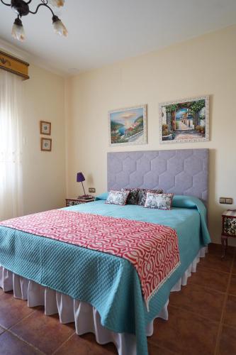a bedroom with a large bed with a blue bedspread at Casa El Sol in Mota del Cuervo