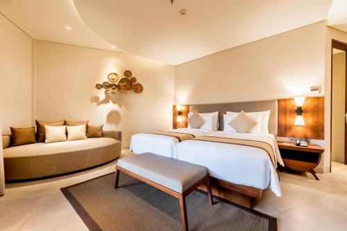 a bedroom with two beds and a couch at tanadewa Resort Ubud Bali by Cross Collection in Ubud